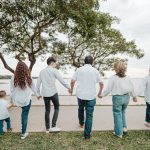 Family holding hands walking by the water