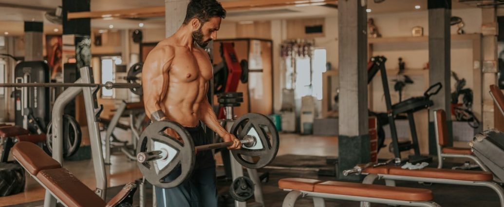 topless man in black shorts carrying black dumbbell photo