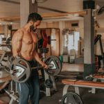 topless man in black shorts carrying black dumbbell photo